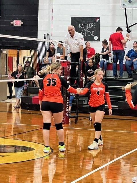 Two girls shaking hands after a volleyball game.