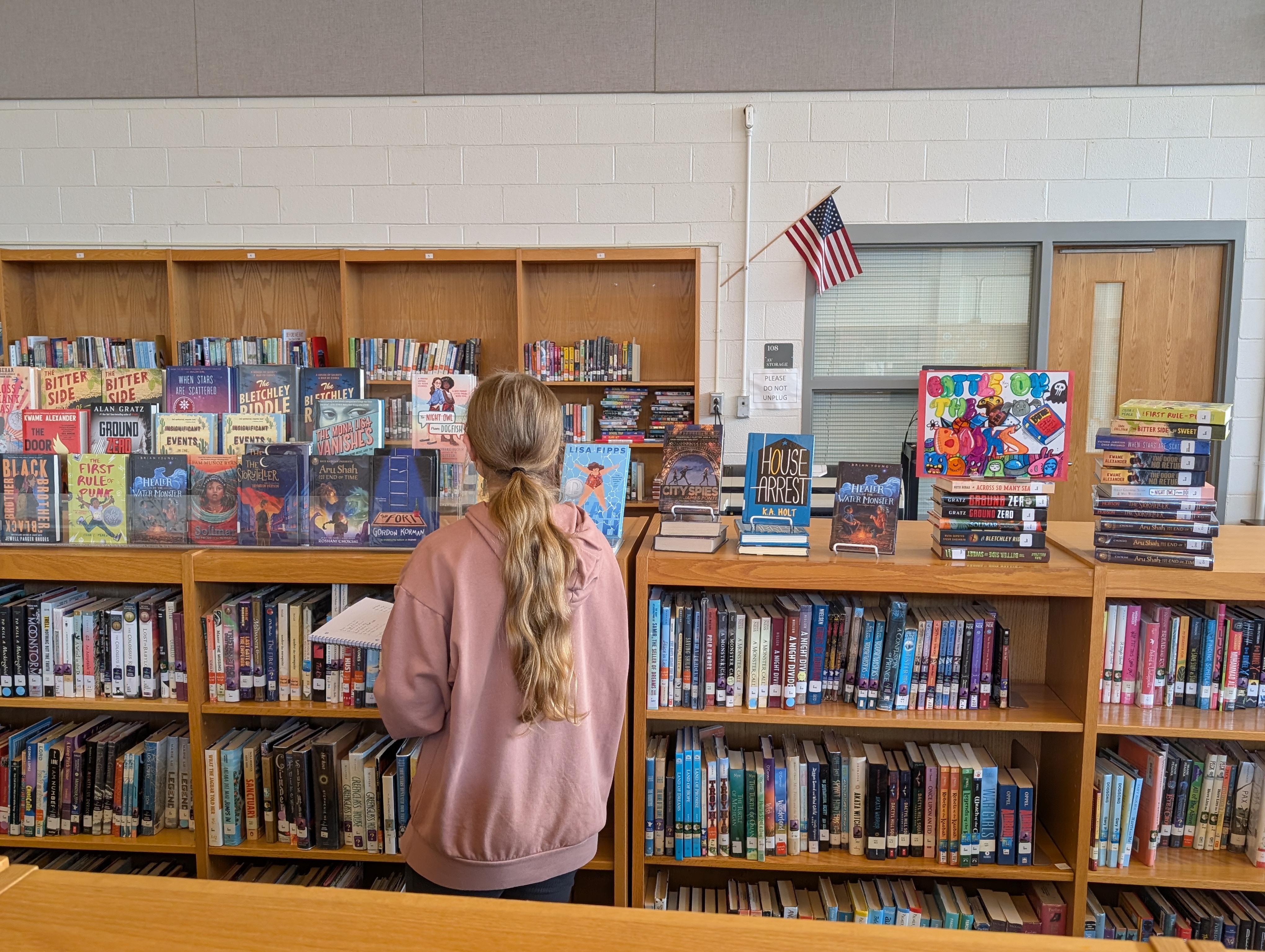 Student in front of Battle of the Books display in media center
