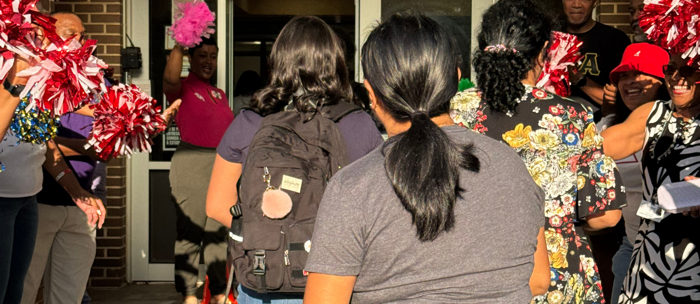 Students entering LGMS flanked by adults with pompoms