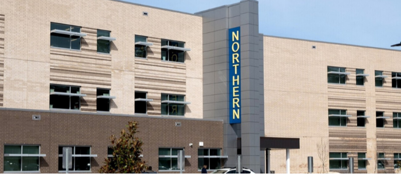 A color photograph of the front of Northern High School with a vertical sign spelling out the name NORTHERN