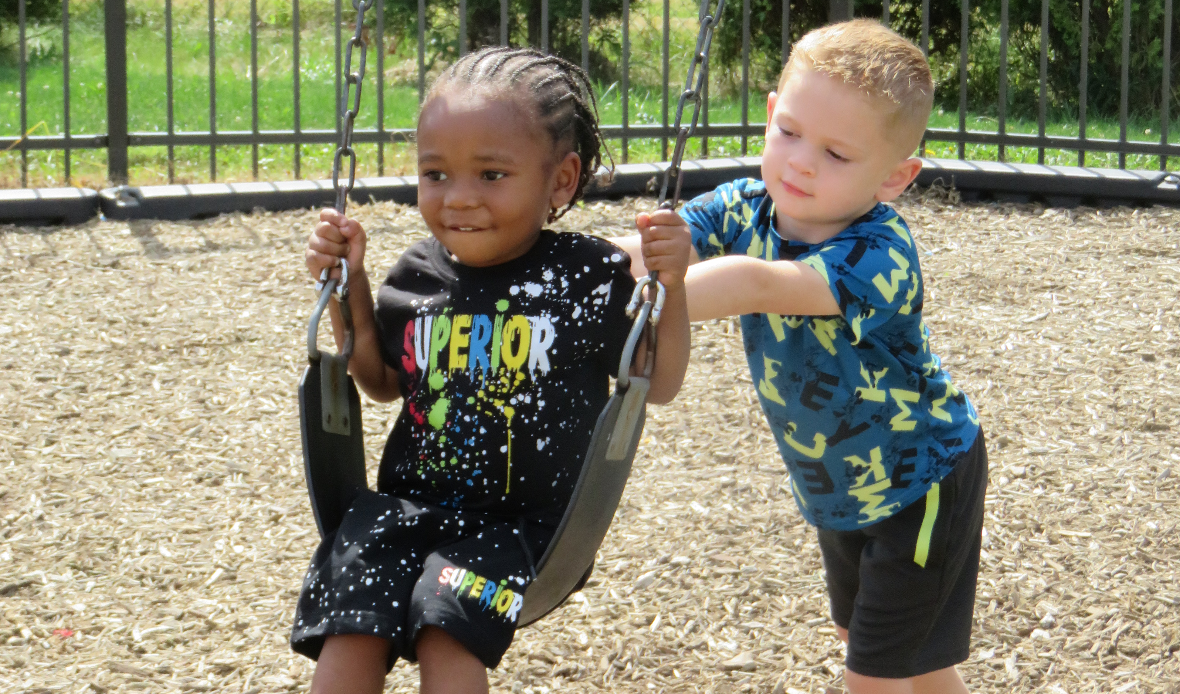 Two preschoolers having fun on the swing set!