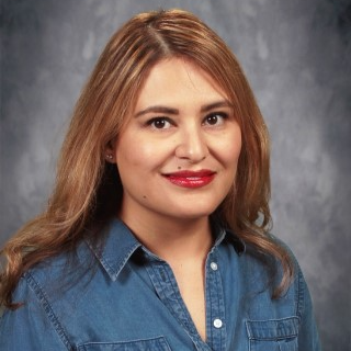 A woman wearing a blue shirt and red lipstick, smiling confidently at the camera.