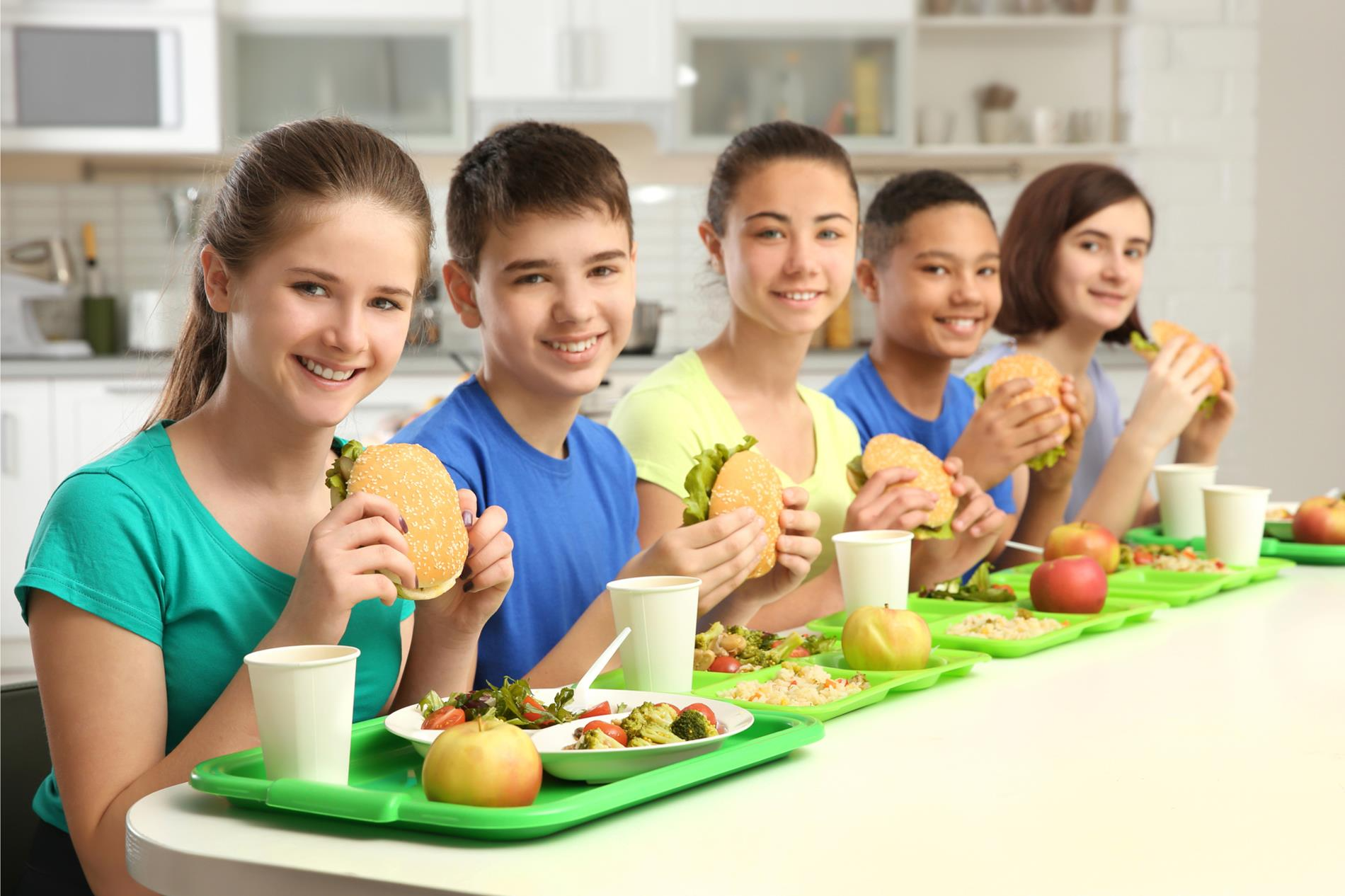 A group of children gathered around a table, enjoying a meal together with various dishes and cheerful expressions.