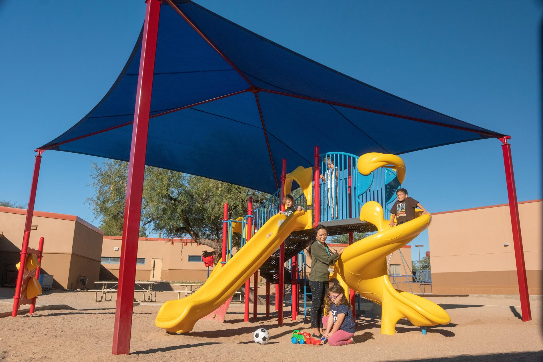 A blue canopy providing shade, set against a clear sky, with sunlight filtering through its fabric.