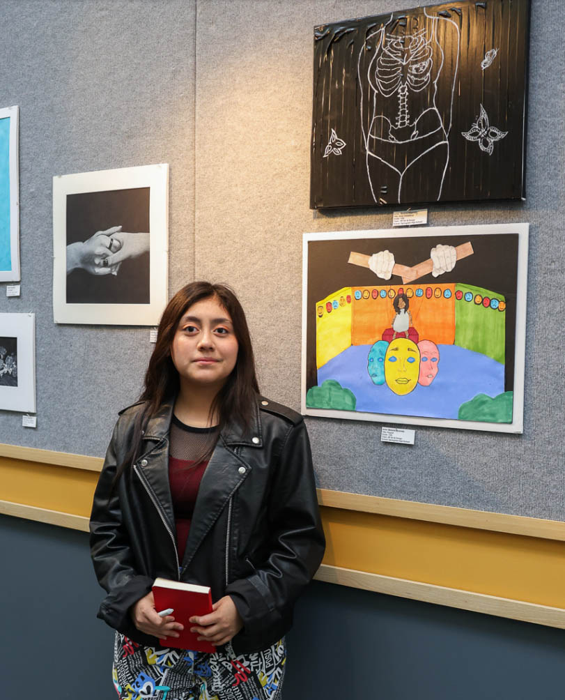 A student poses in front of her artwork