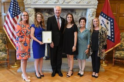 A photo of a biliterate student with the Governor of Arkansas
