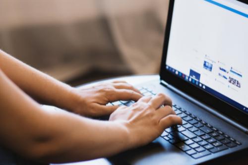 Hands typing on a laptop keyboard.