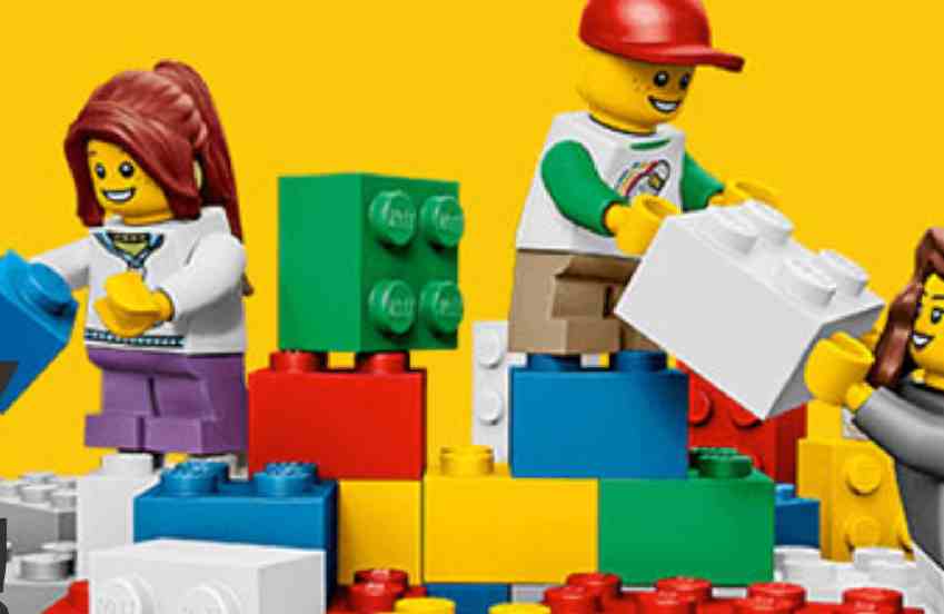 A group of LEGO figures stands triumphantly on a colorful pile of bricks, showcasing creativity and playfulness.