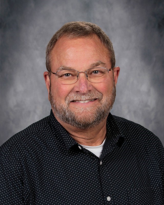 A smiling man with glasses and a beard, exuding a friendly and approachable demeanor.