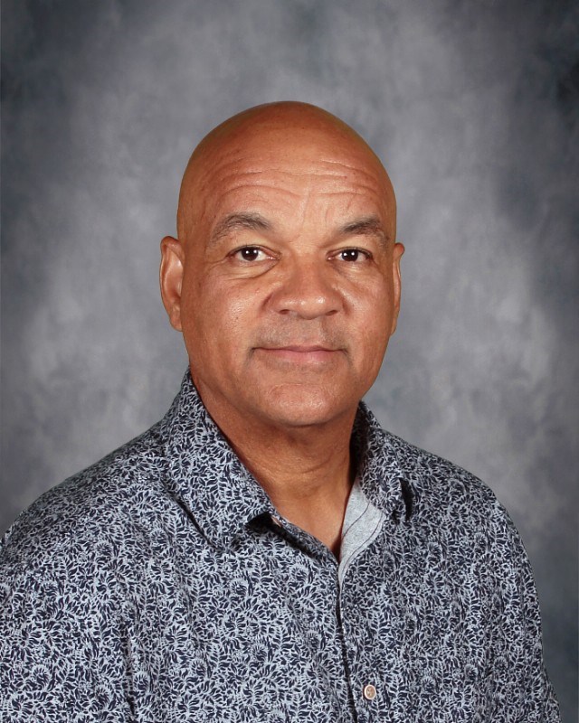 A person wearing a patterned shirt poses for a portrait, with a blurred background enhancing focus on their attire.