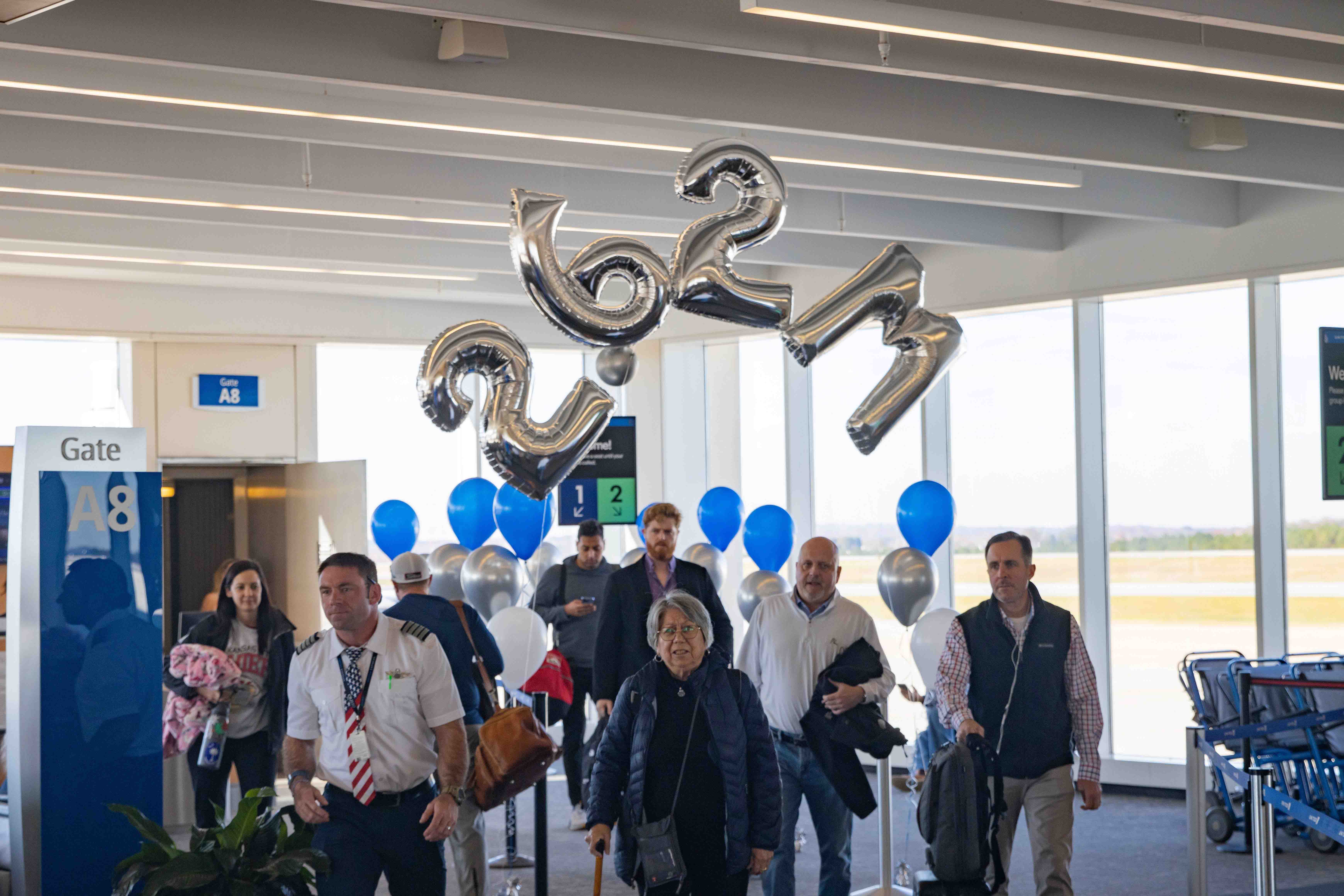 Passengers exit terminal with record balloons above them stating 262 million