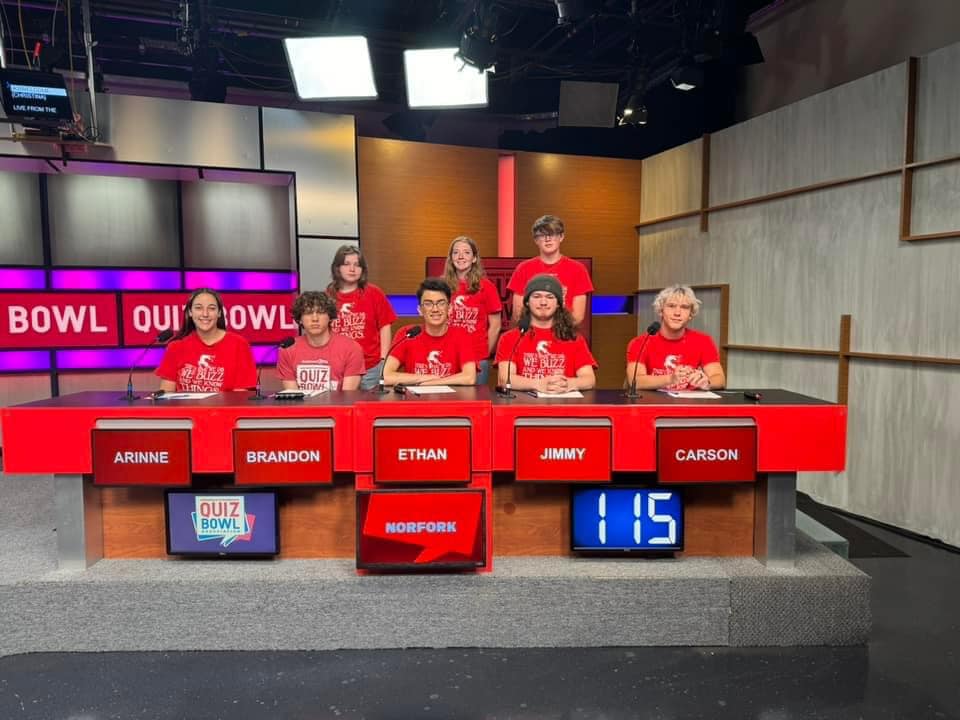 Team posing in front of a news set.