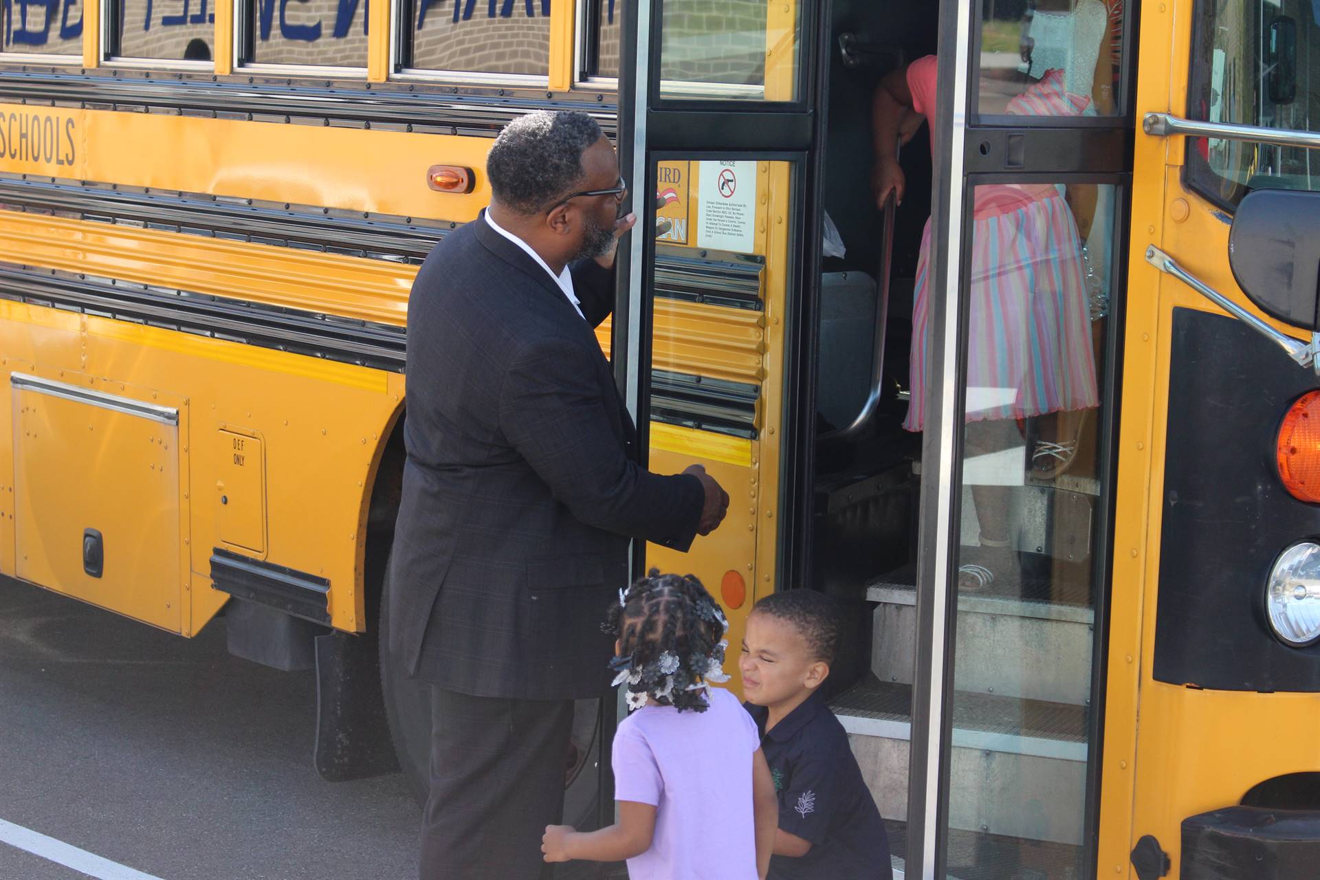 teacher welcoming a student thats taking off the school bus