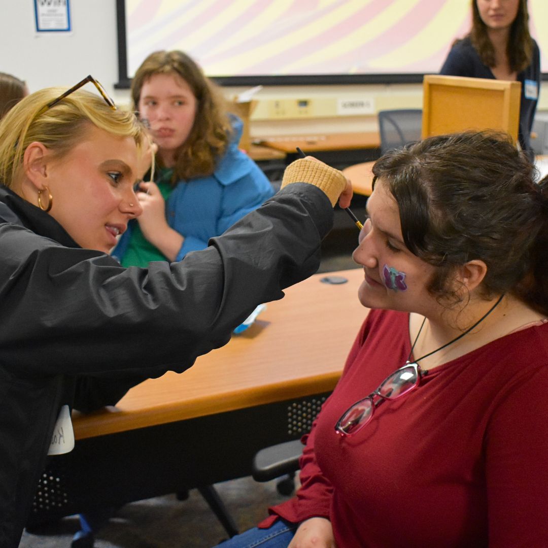 Student getting her face painted by a volunteer