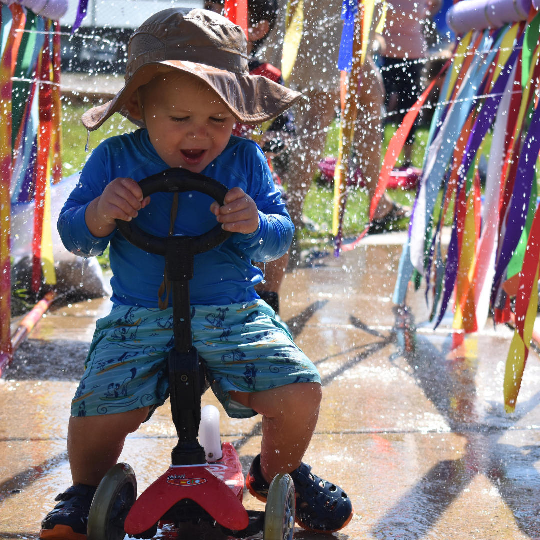 Boy going through sprinkler with his bike