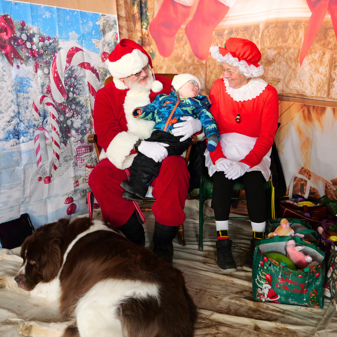 Child on Santa's lap with Mrs. Claus and their dog