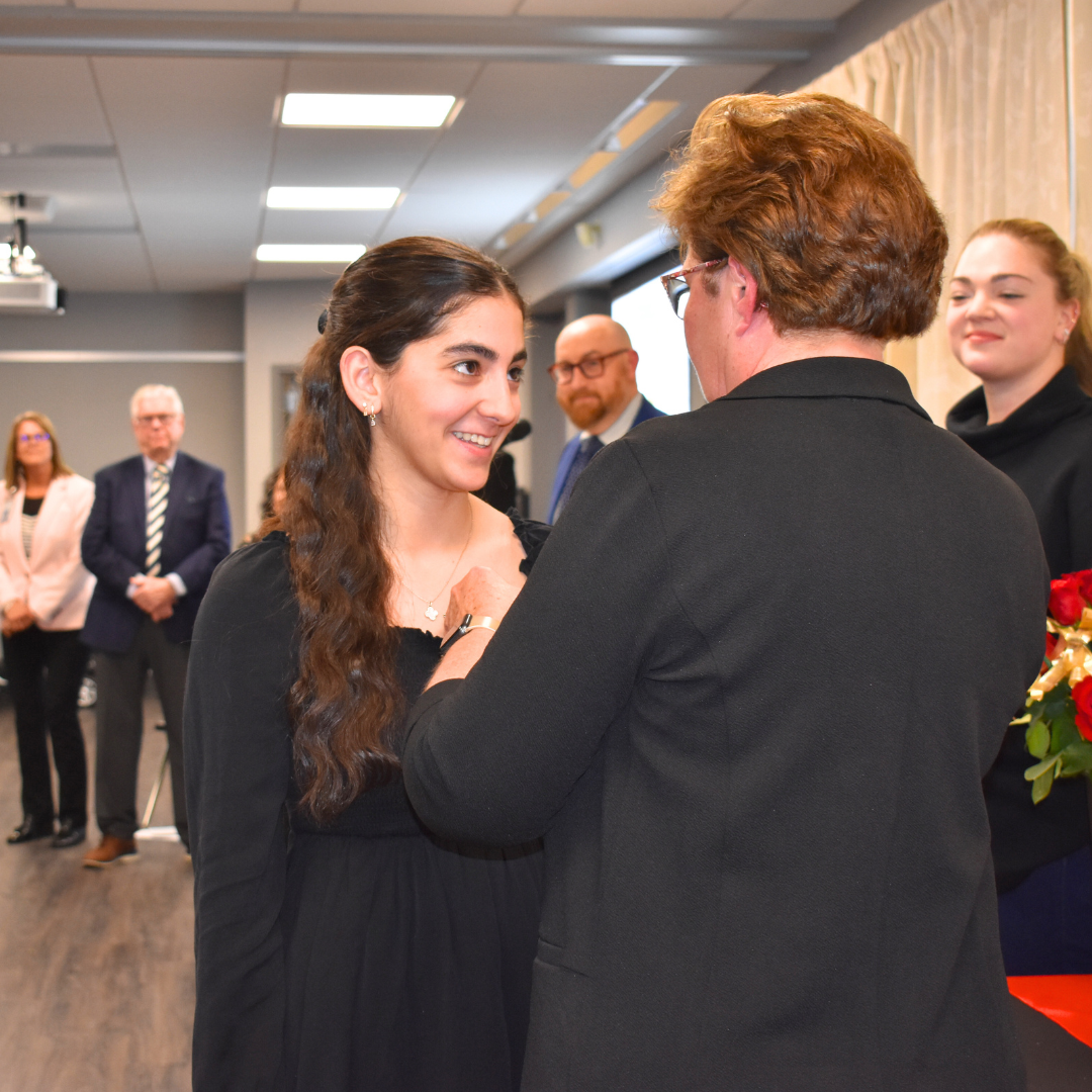 An instructor pinning a student with her CNA pin