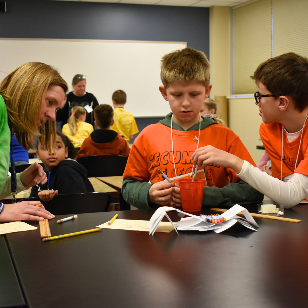 Two students testing their science experiment while a judge looks on
