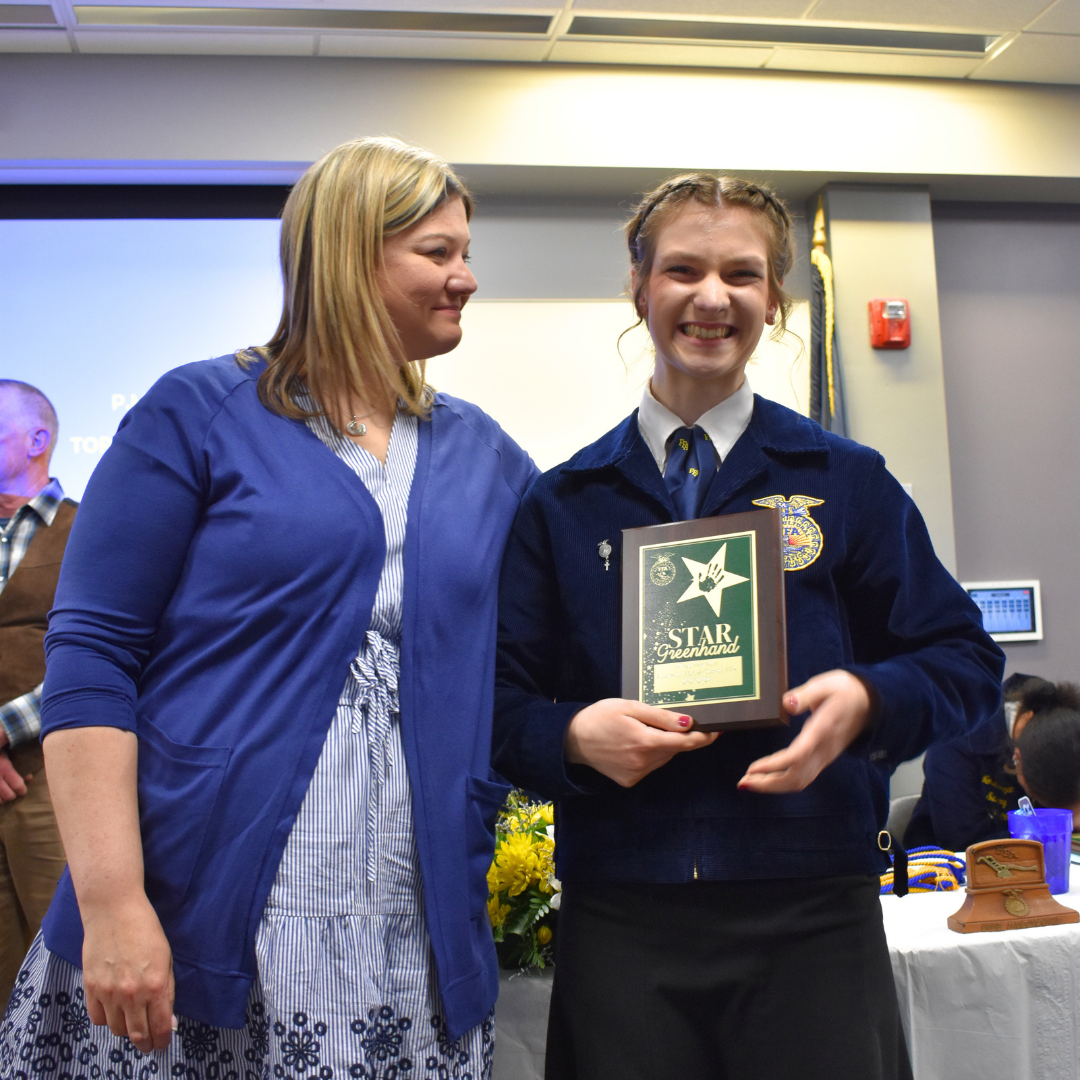 Student receiving her award as her instructor smiles at her