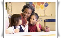 A teacher interacts with two young children at a table, fostering a warm and engaging learning environment.