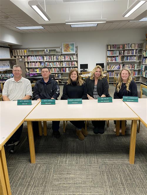 board members smiling sitting on a library desk