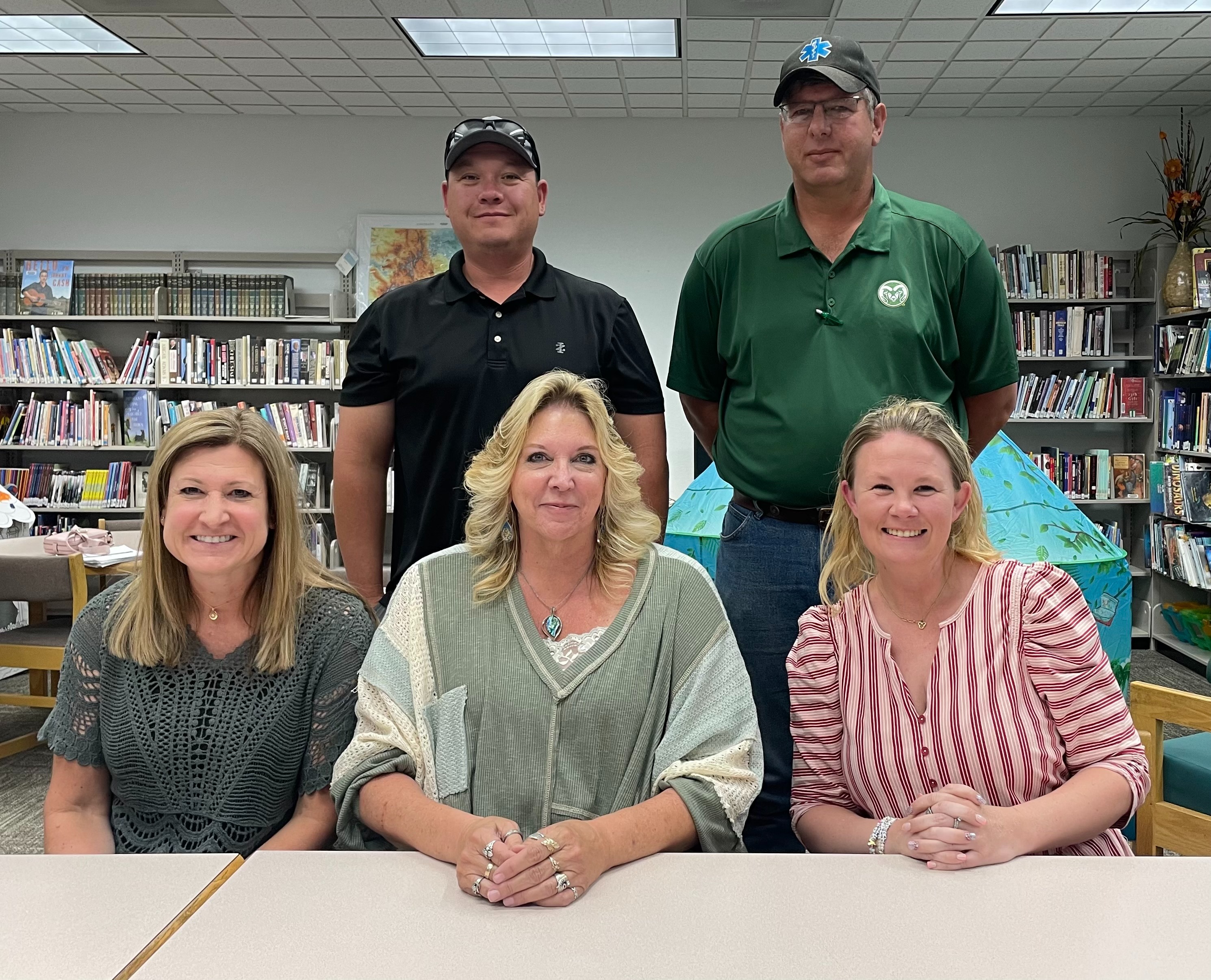 board members smiling sitting on a library desk