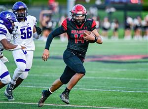 Male athlete running with football in hand on football field.