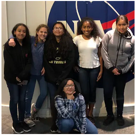 A group of young people posing in front of a NASA sign.