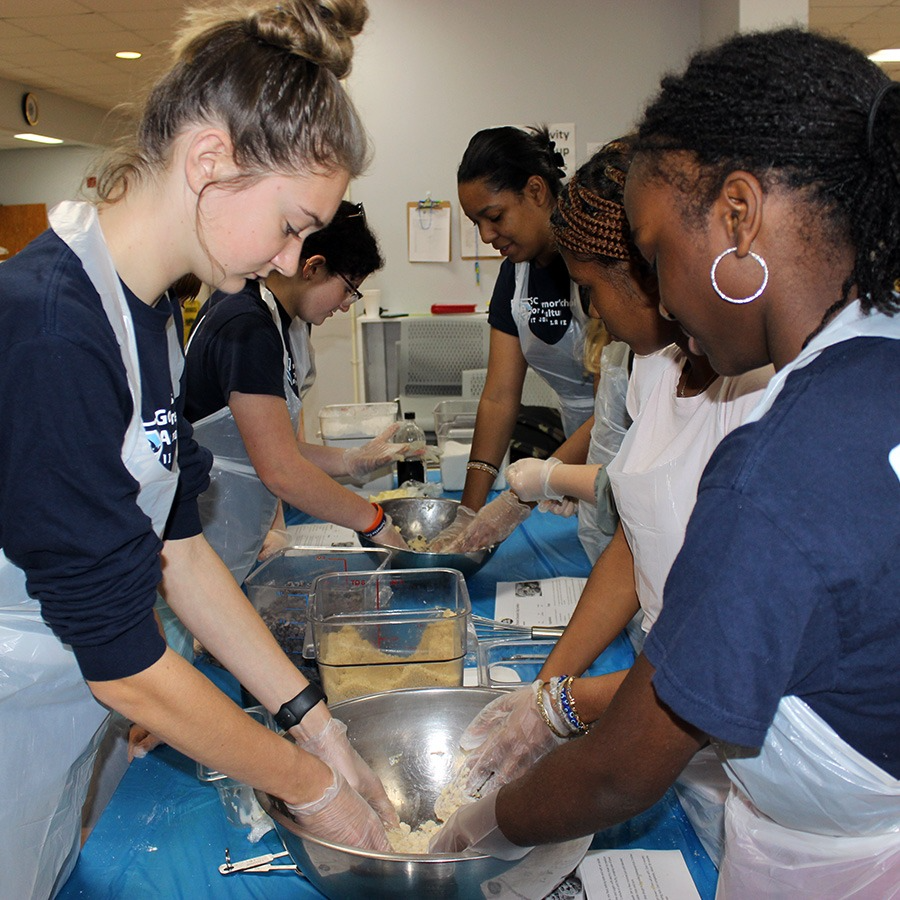 Students work in the kitchen to make Christmas cookies.