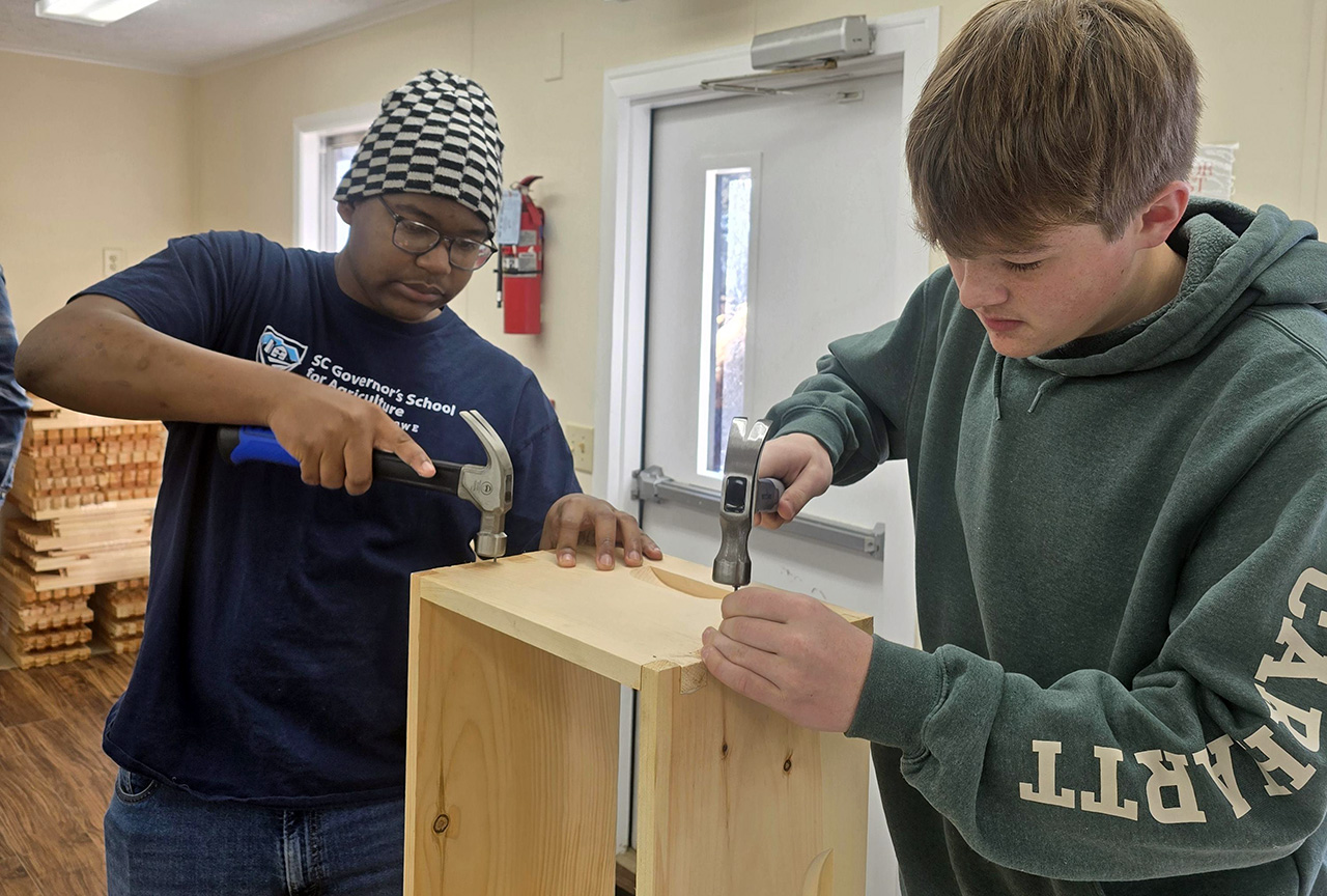 Two of our students work on building bee boxes.