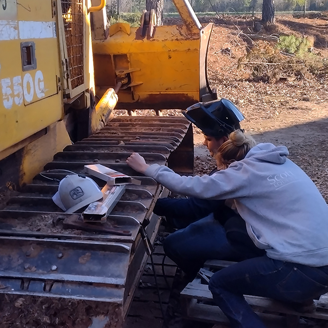 Students closely examine a piece of heavy equipment on the farm.