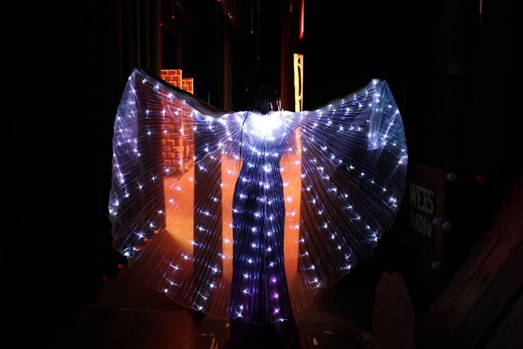 Actor in dragon light suit standing with wings extended out