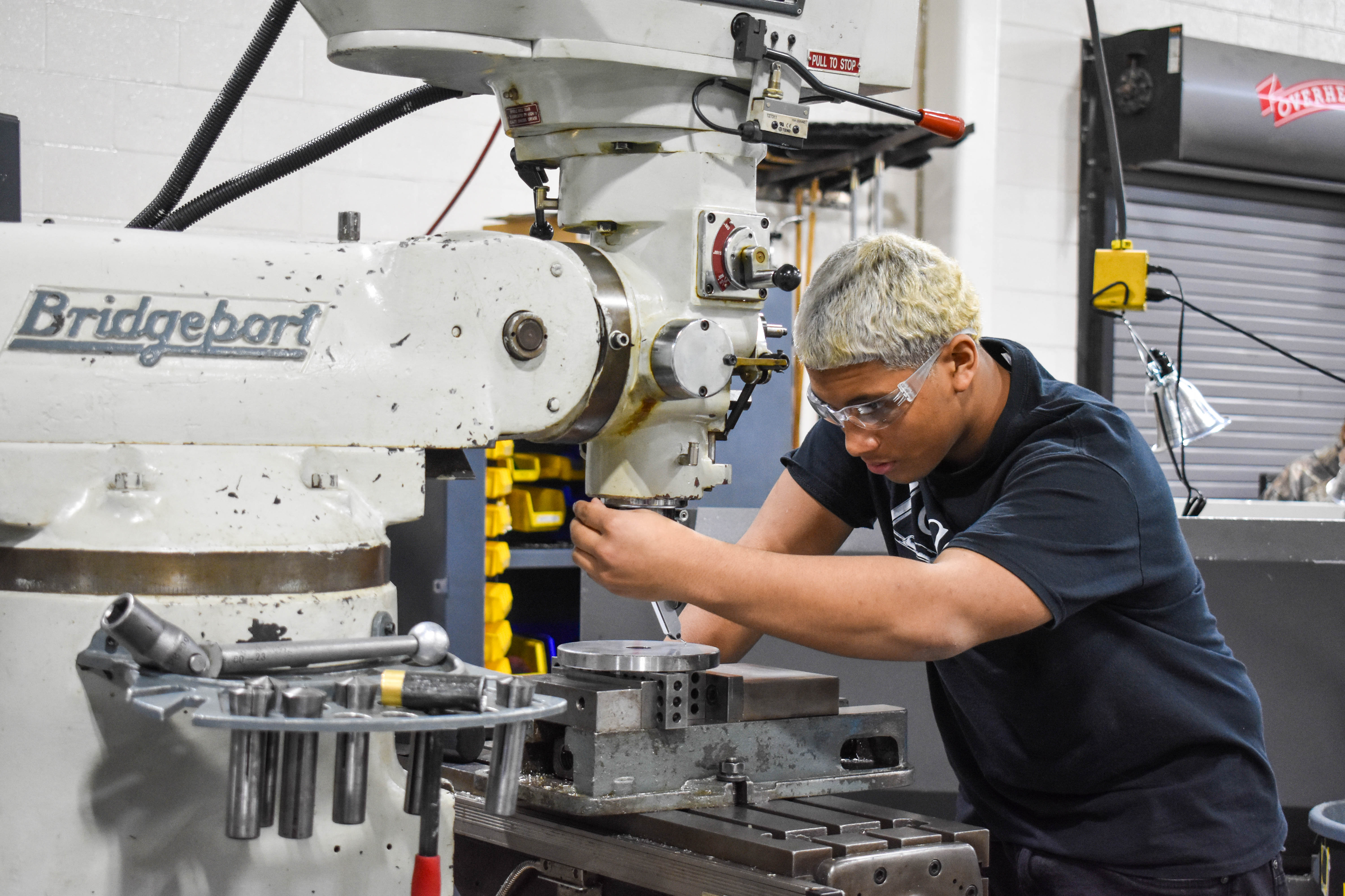 Student operating a machine in the Machining and Computer Aided Manufacturing program