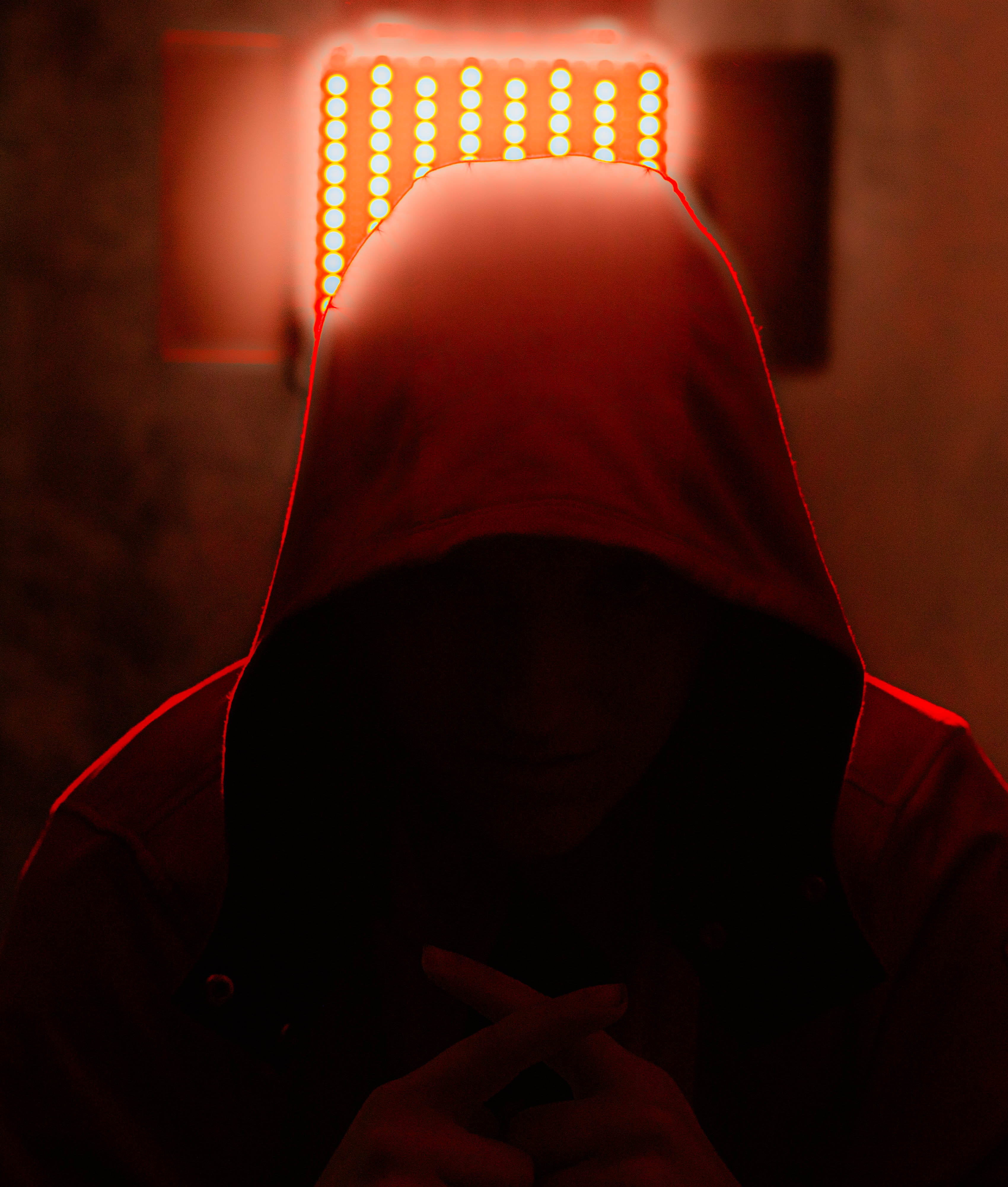 hooded figure in front of a bright light