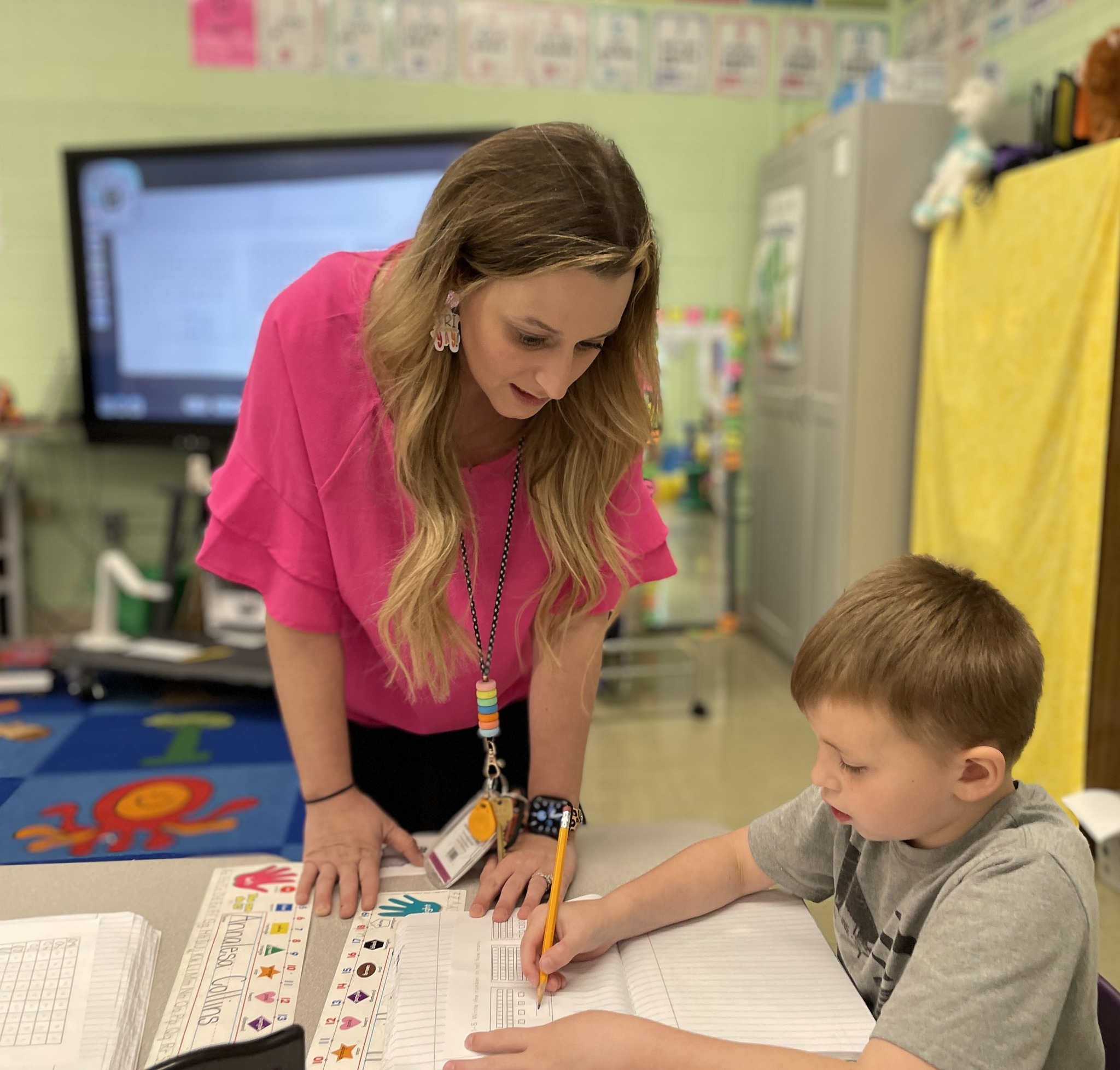 teacher helping student in classroom