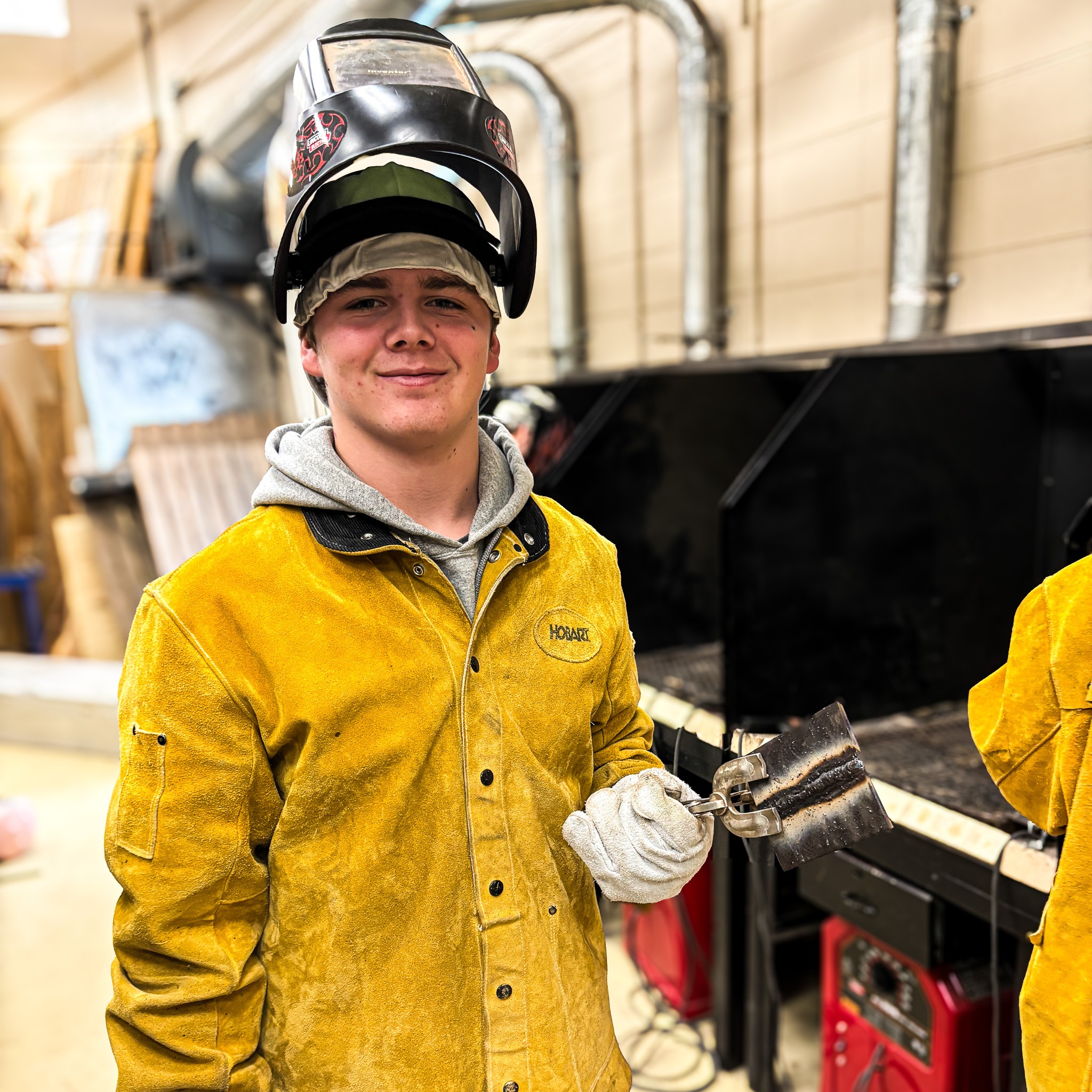 a student holds welding tools while in a class