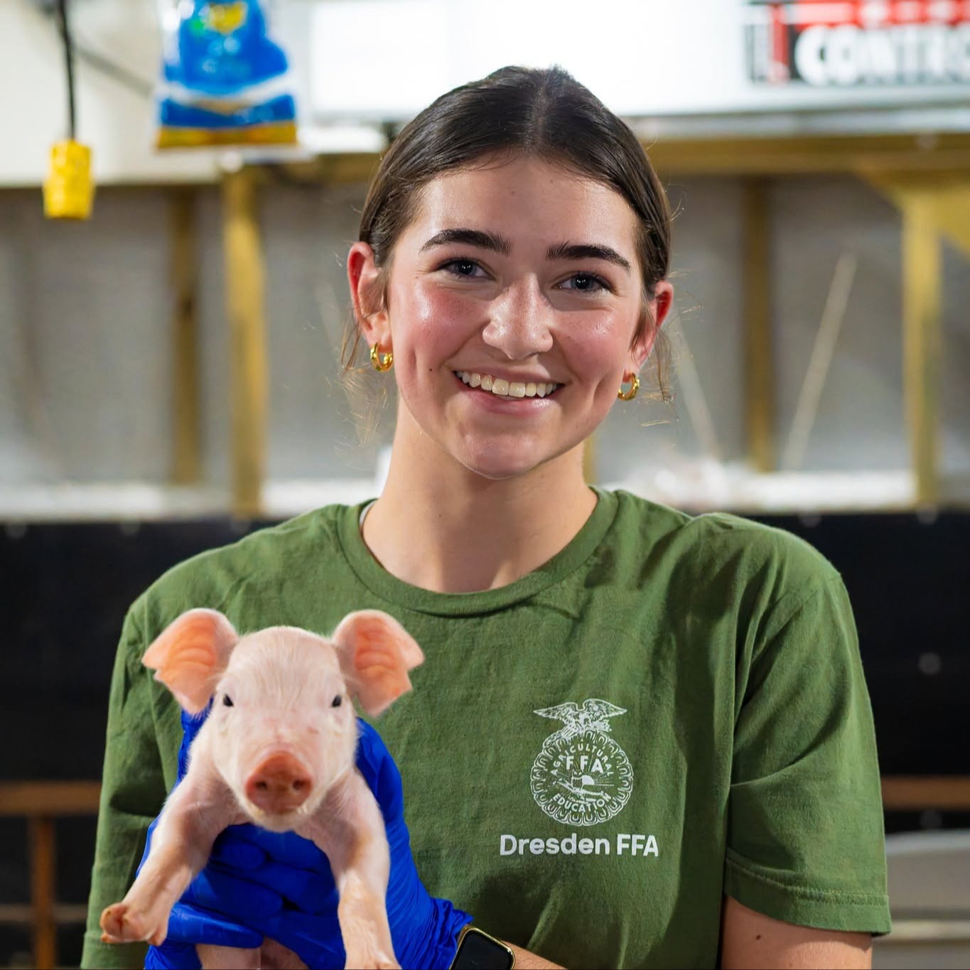 a student in a green shirt holds a pig