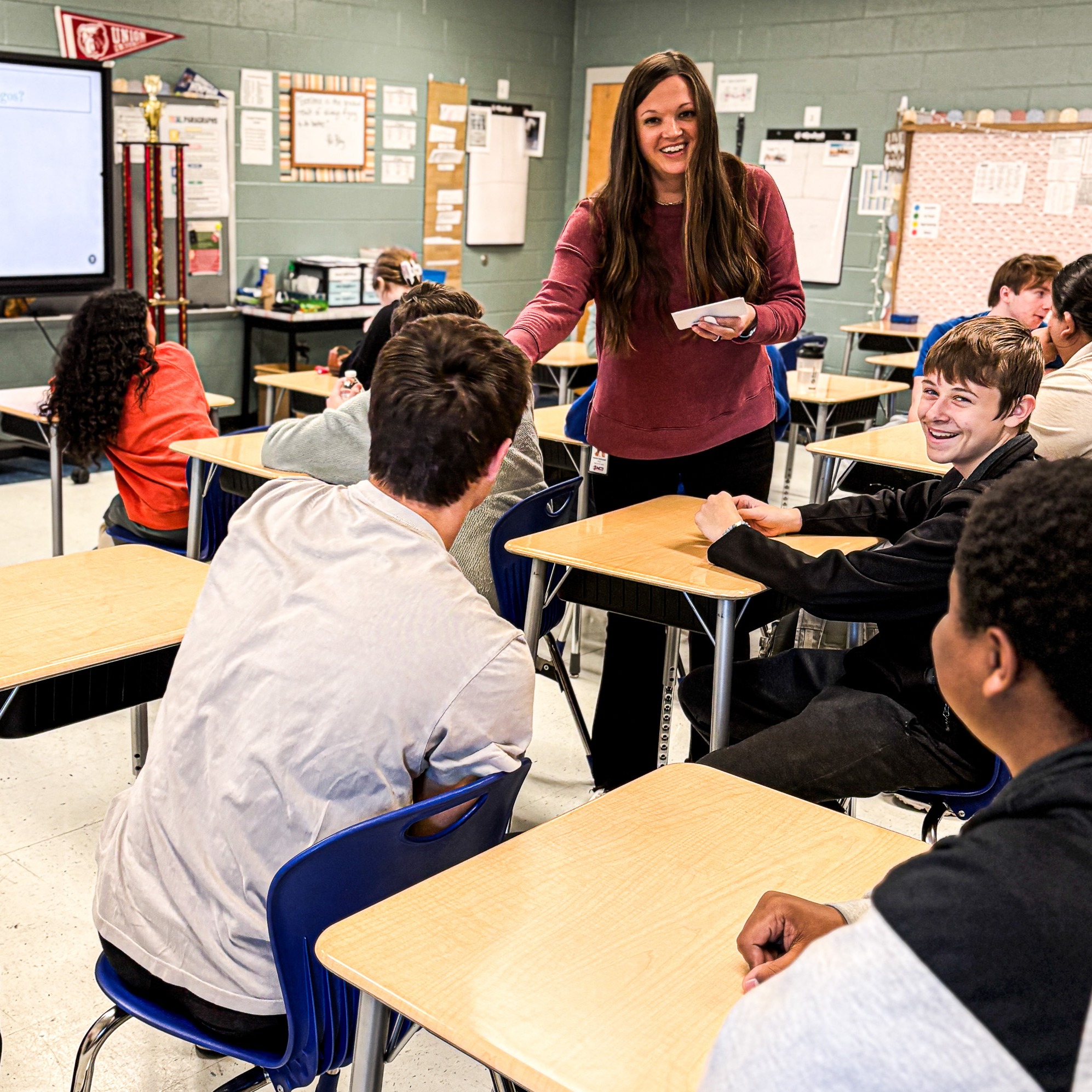 a teacher and student smile while passing out papers