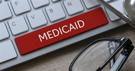 Medicare sticker on a laptop computer with glasses and a pen.