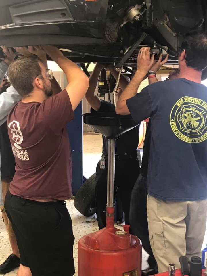 Two males working under a car in an automotive shop