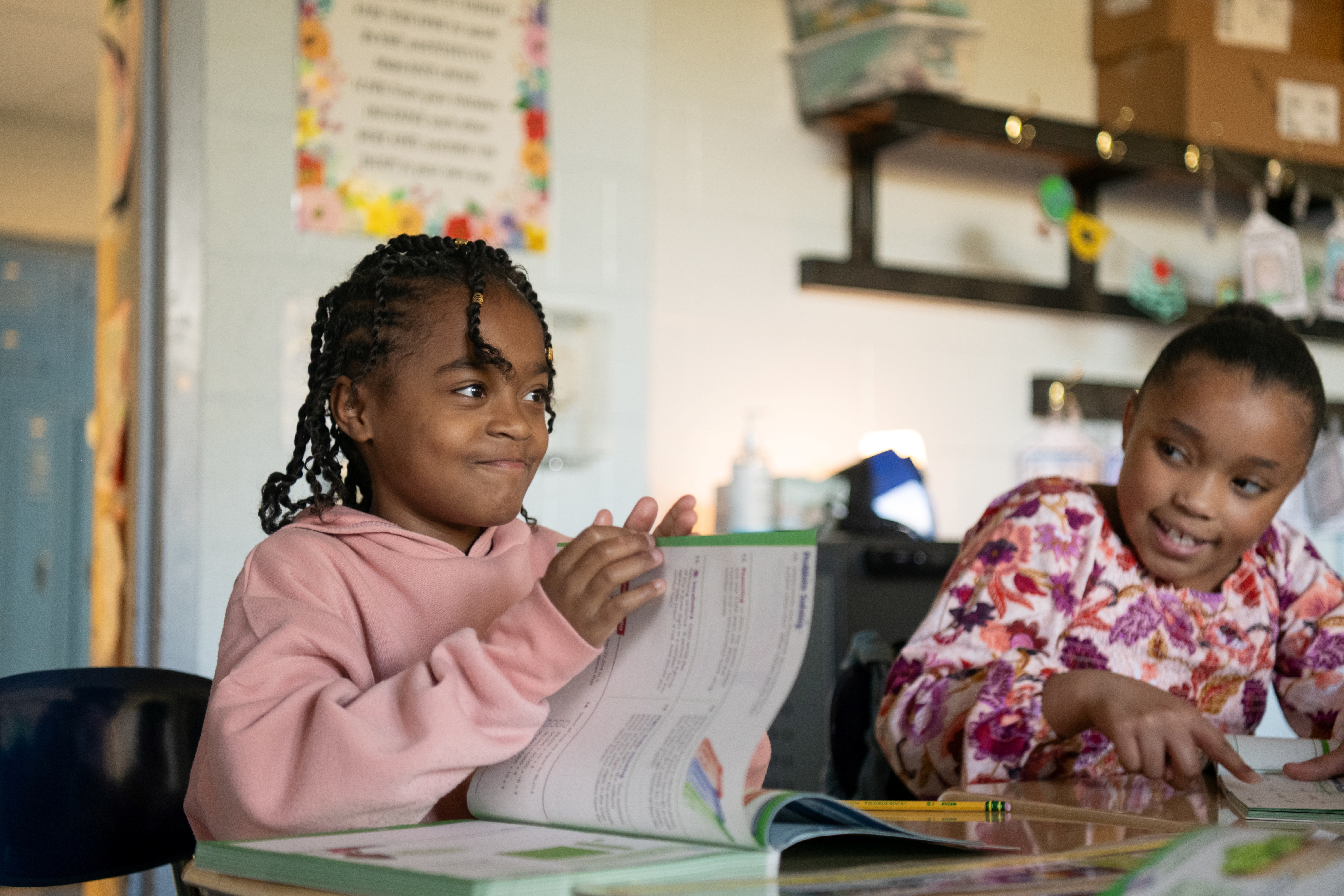 two students smiling and looking at their workbook