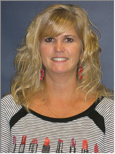 A woman with wavy blonde hair, wearing a striped shirt with red accents and earrings, smiles at the camera against a blue background.