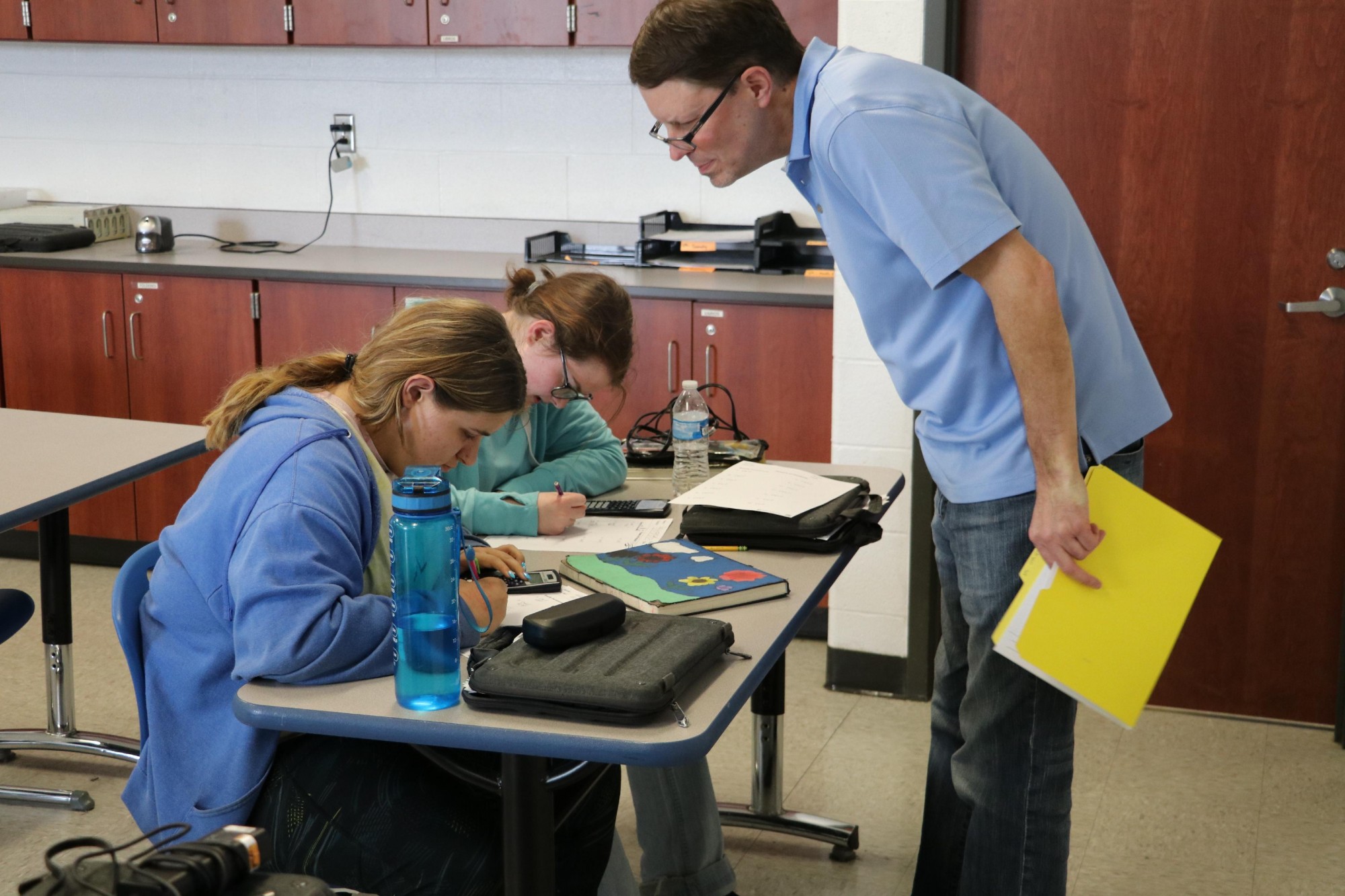 teacher helping 2 students with their assigments