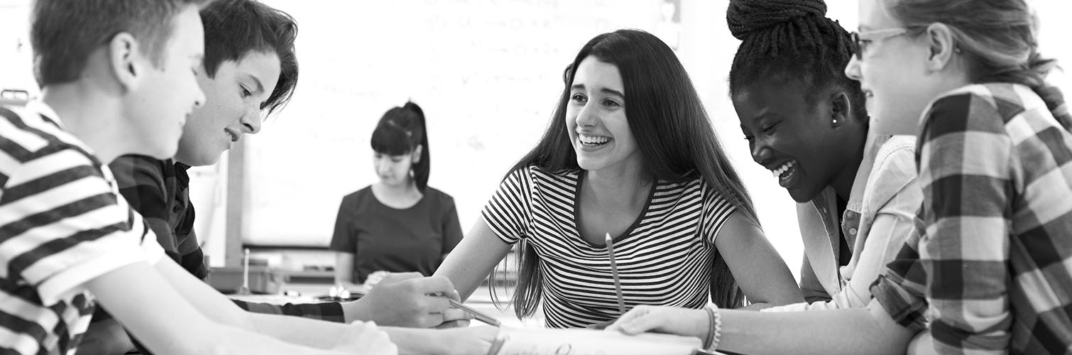 A group of young people gathered around a table, engaged in collaborative work or discussion.