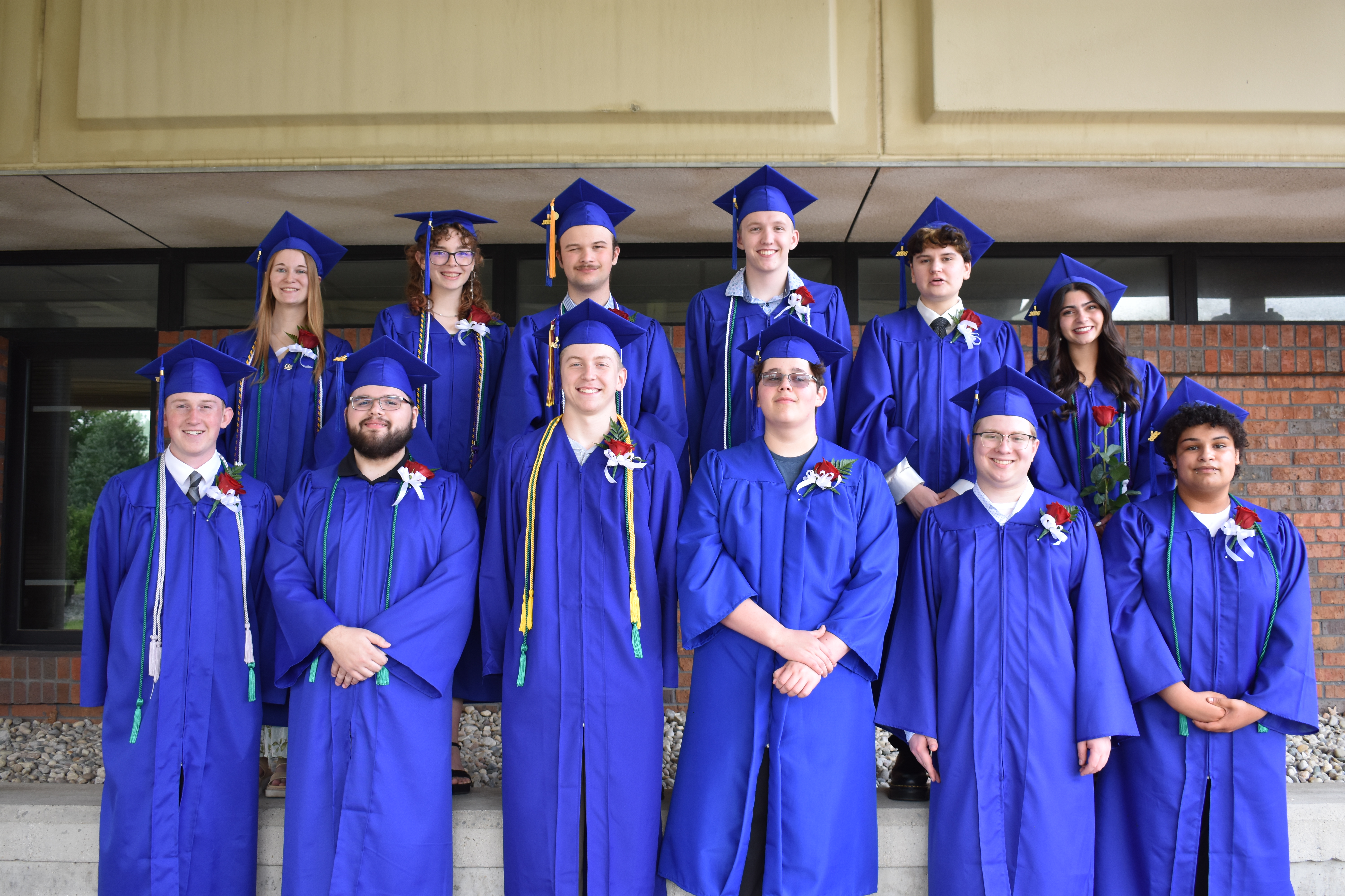 A photo of the 2026 graduates standing outside next to brick wall