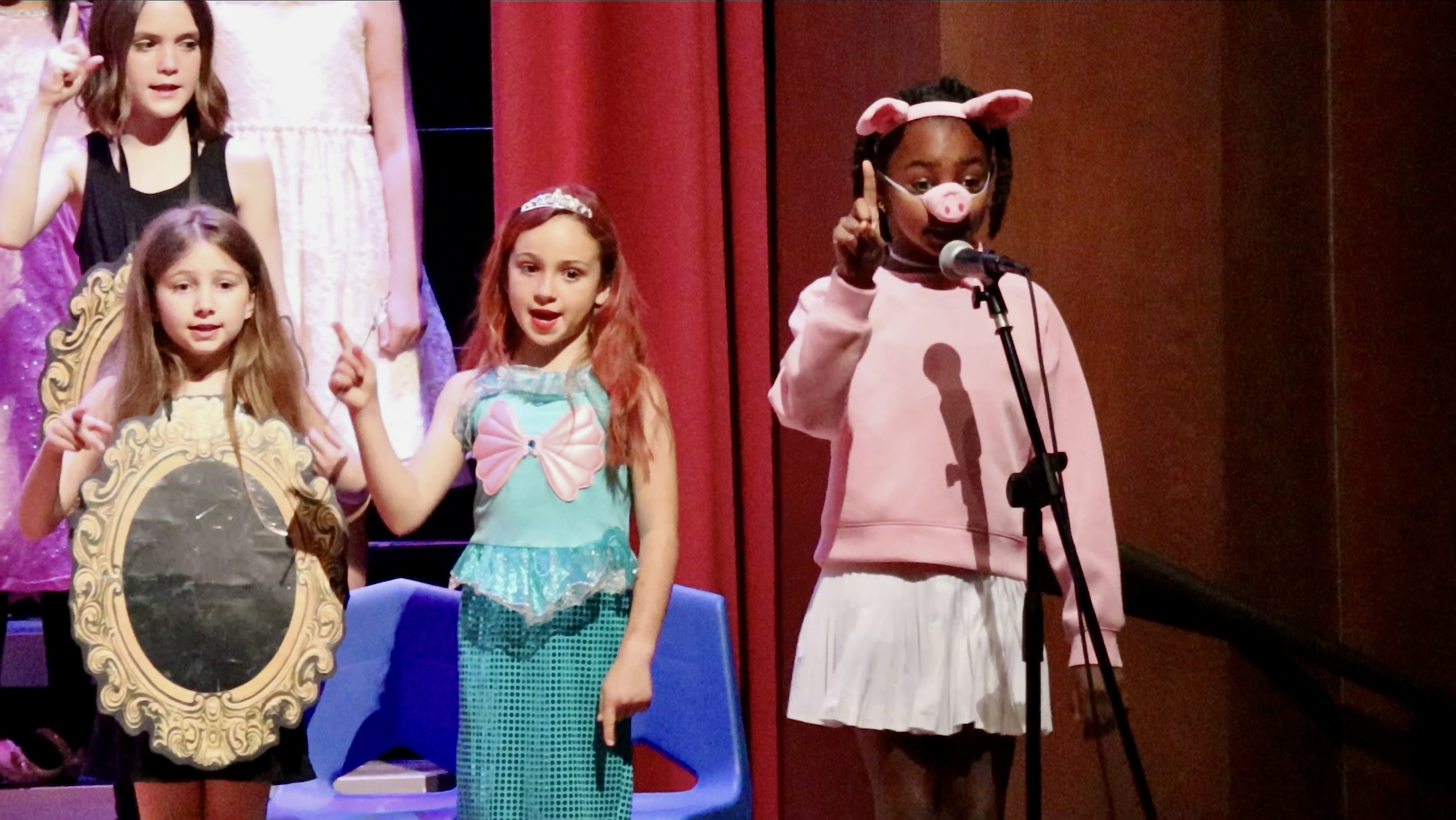 Students in costume singing on stage.
