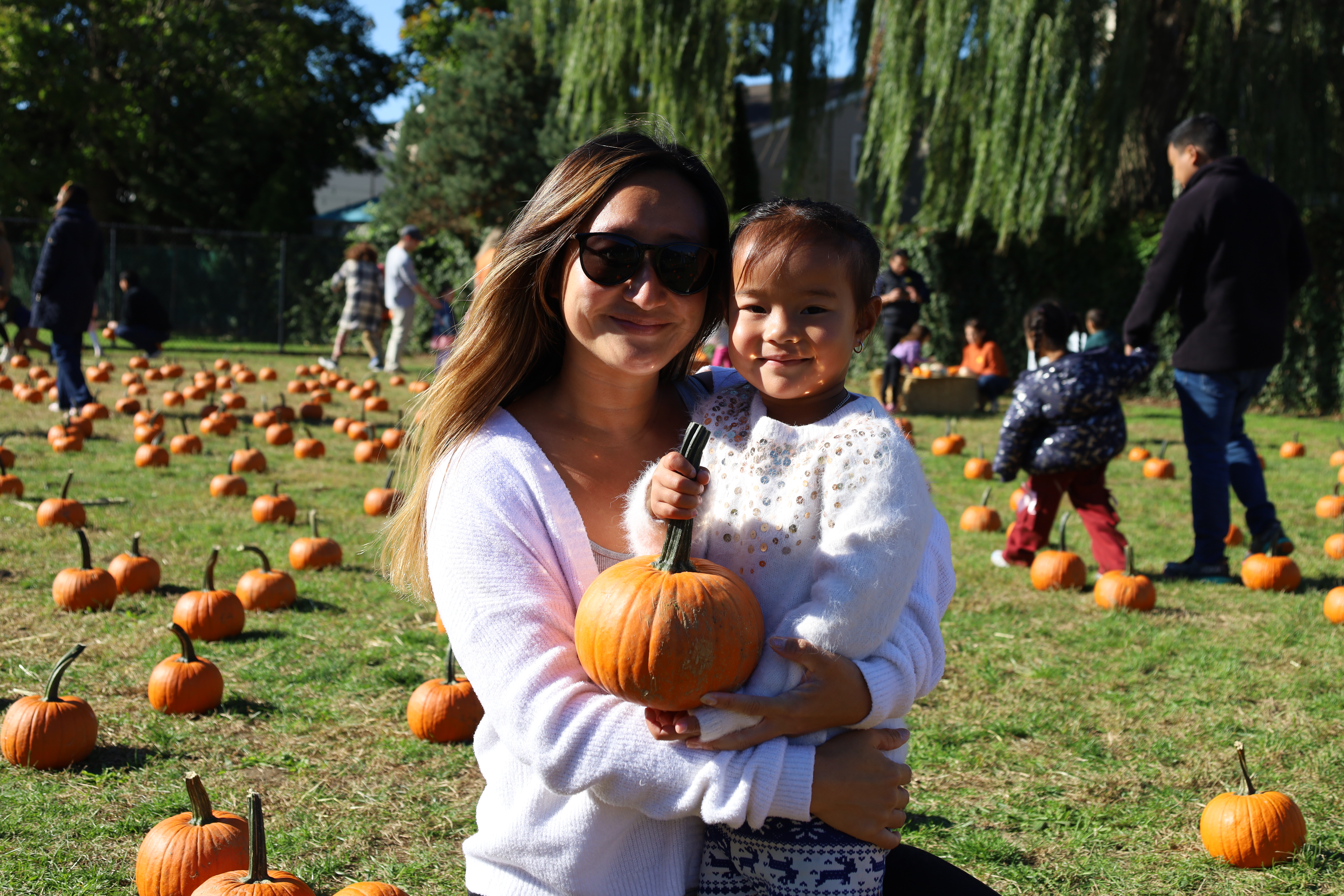 Student smiling with parent holding pumpkin.