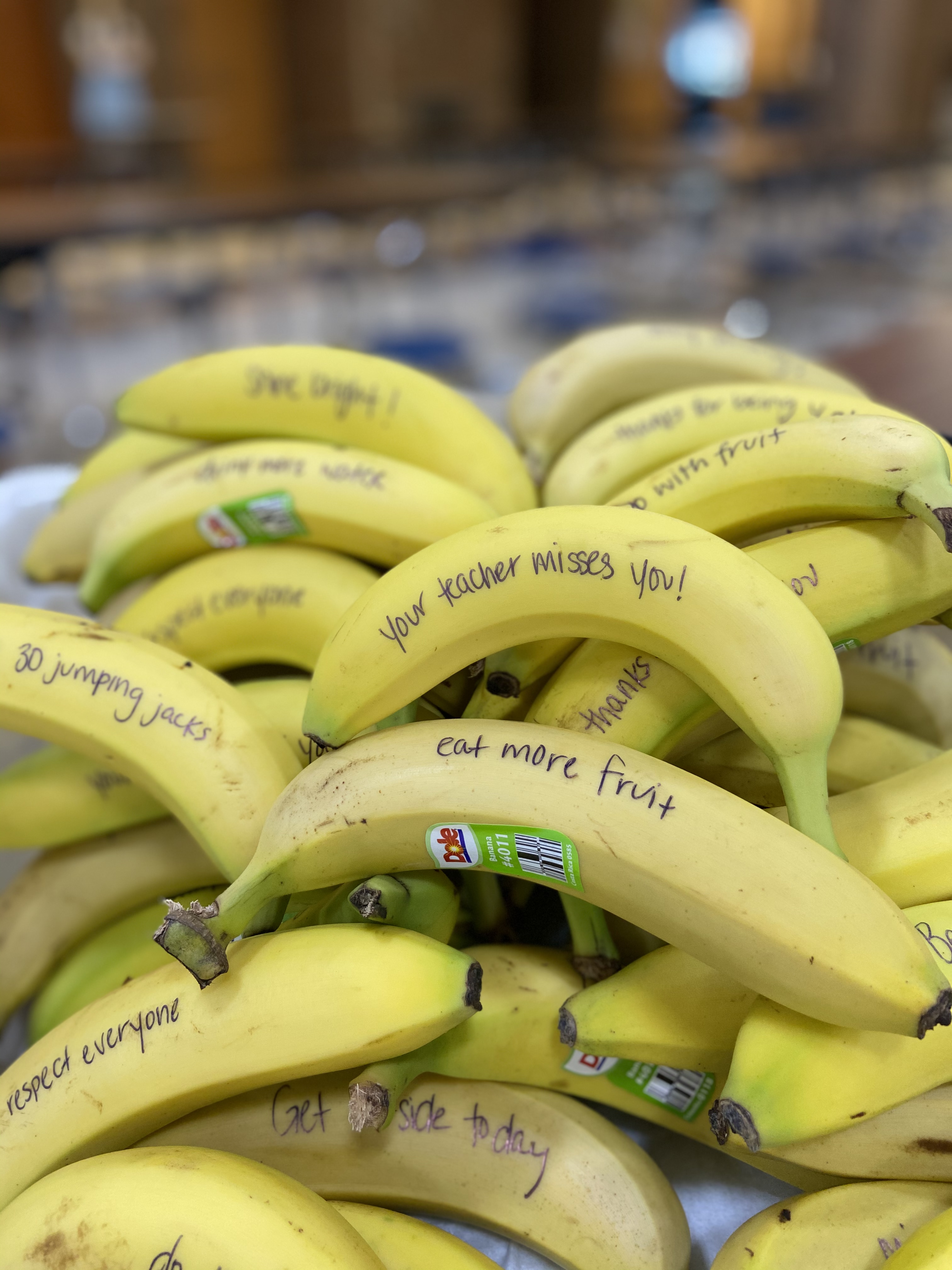 A pile of yellow bananas with handwritten messages on their peels, including phrases like 'You matter!' and 'Eat more fruit!'.