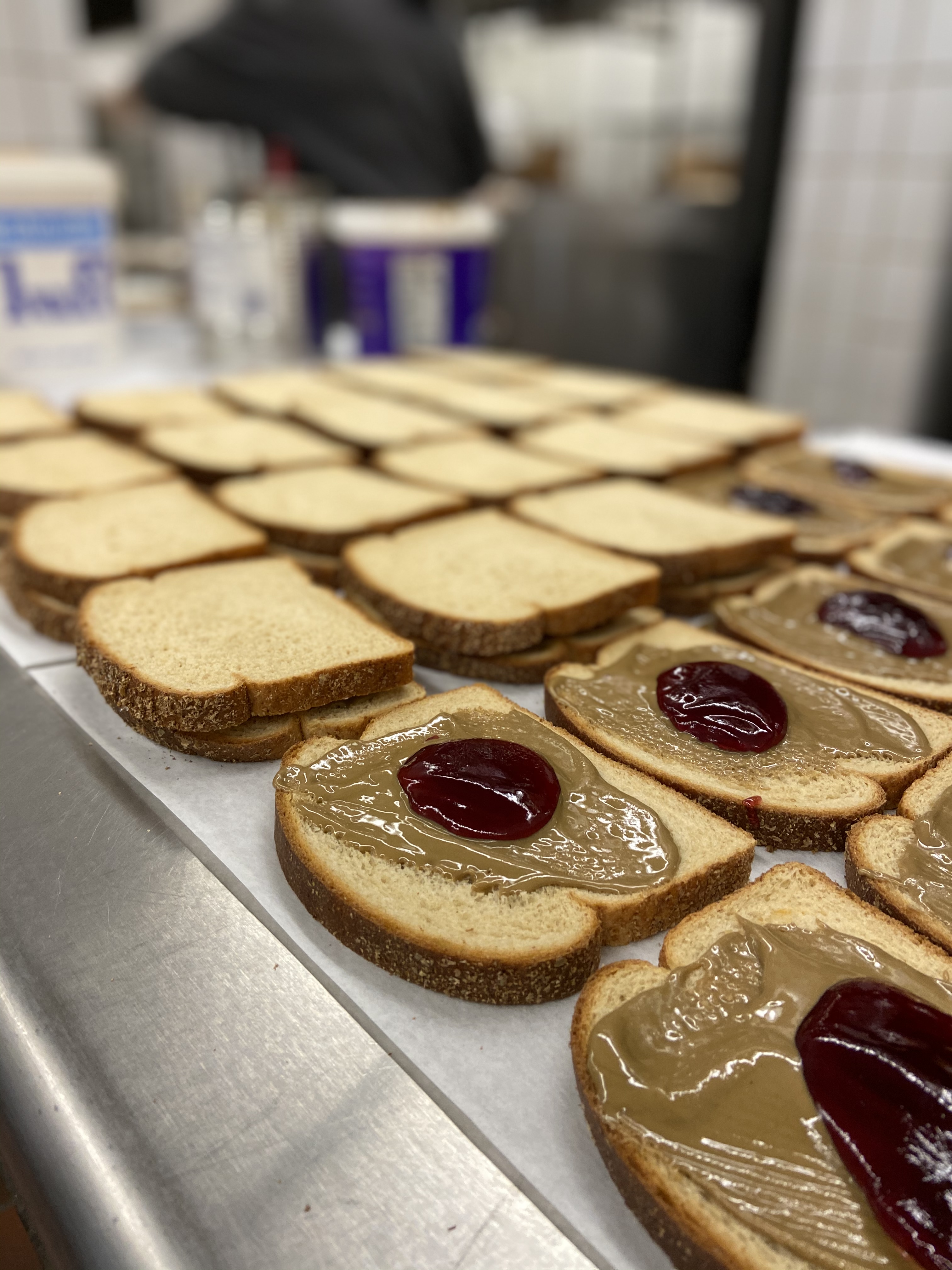 A close-up view of several slices of bread spread with peanut butter and topped with jelly, arranged neatly on a table.