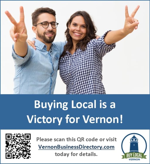 A man and a woman are smiling and making peace signs with their fingers, promoting the message 'Buying Local is a Victory for Vernon!' along with a QR code and website link for more information.